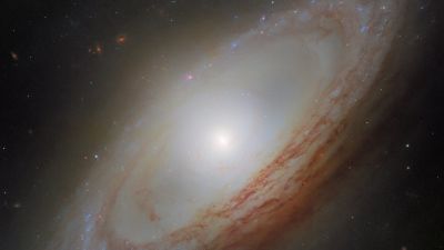Imagen del Hubble de la galaxia espiral NGC 4698 en el Cúmulo de Virgo, con sus brazos espirales polvorientos en forma de anillo rodeando un bulbo brillante que se extiende por encima y por debajo del disco.